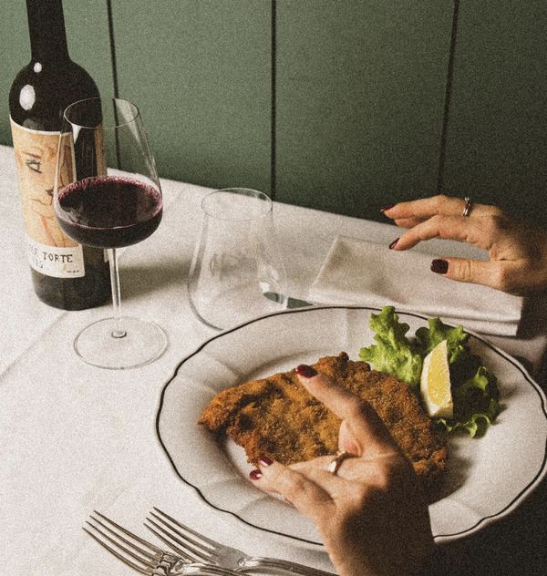 Cotoletta alla milanese e un calice di rosso contro la boiserie verde