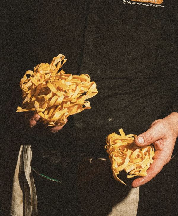 Mani che reggono nidi di tagliatelle fresche