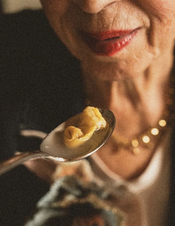 Una signora assaggia il tortellino in brodo